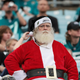 A man dressed as Santa at a Jacksonville Jaguars football game with fans in t-shirts in the background.